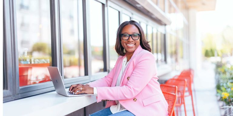 Meka White Morris, chief revenue officer of the Minnesota Twins sitting at a table outside working on a laptop.