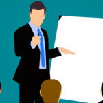 A person standing in front of a group of people presenting with a white board.