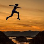 A women jumping across a small river will running