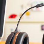 A black and brown headset placed next to a laptop with a black screen and a blurry background.
