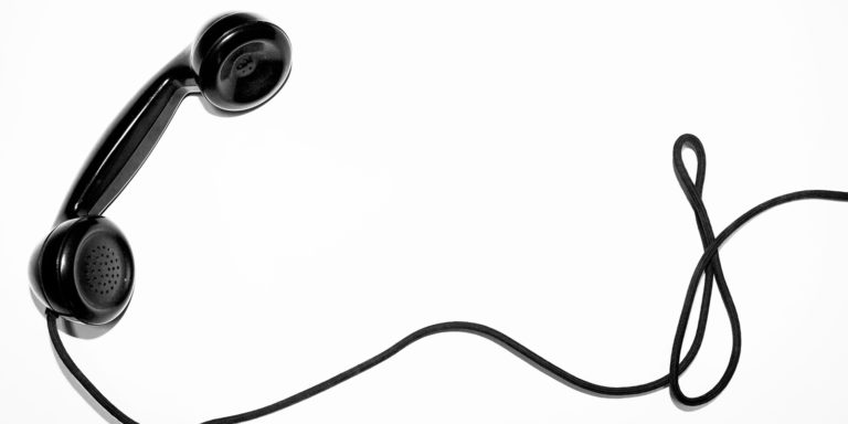 A black telephone with a black cord on a white background