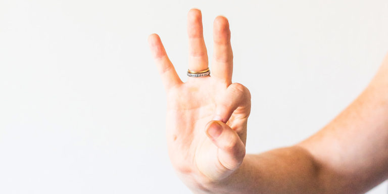 Person holding up three fingers with a white background.