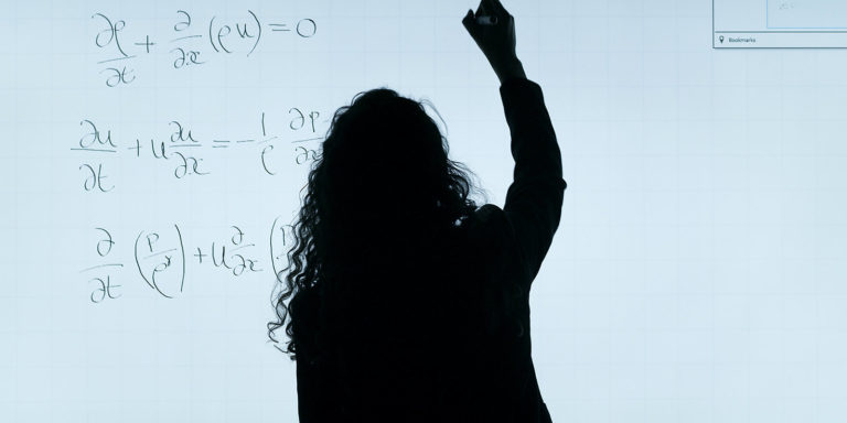 Woman in black writing out a formula.
