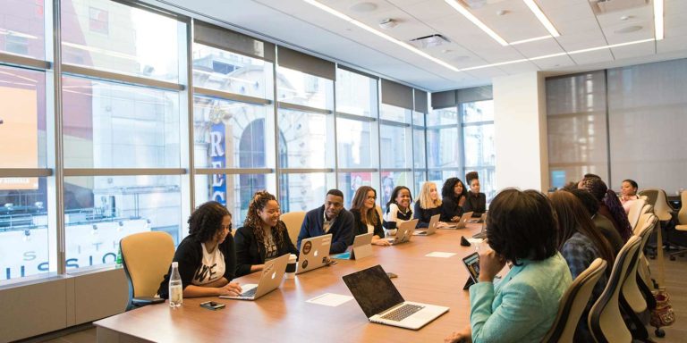 At a conference table sits a large group of men and women.