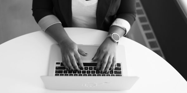 A black and white image of hands on a laptop keyboard.