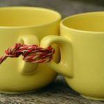 Two yellow cups tied together by a red string.