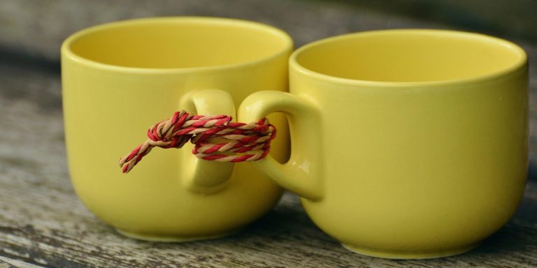 Two yellow cups tied together by a red string.