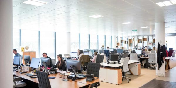 An office space with desks and chairs and people.