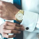 A man adjusts his sleeve with a watch on his wrist.