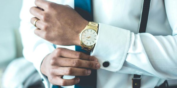 A man adjusts his sleeve with a watch on his wrist.