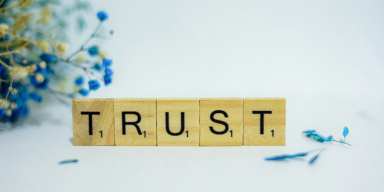 The word trust spelled out with scrabble tiles.