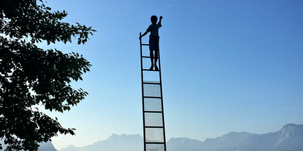 A person climbs a ladder that stands above a body of water.