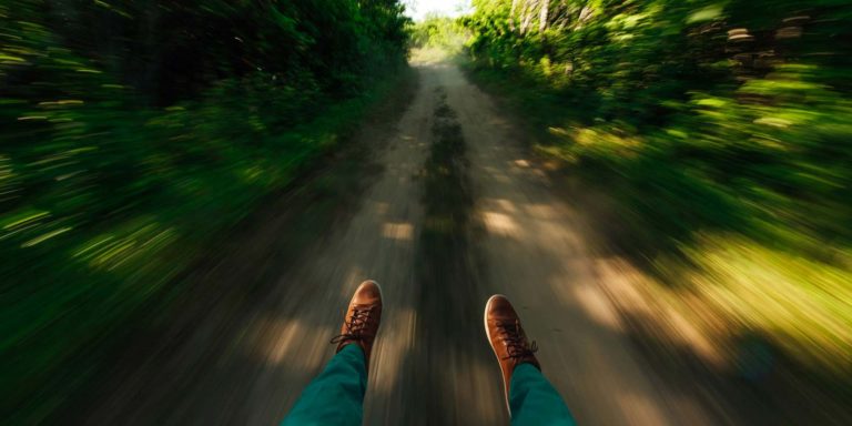 A pair of feet flying through a wooded trail.